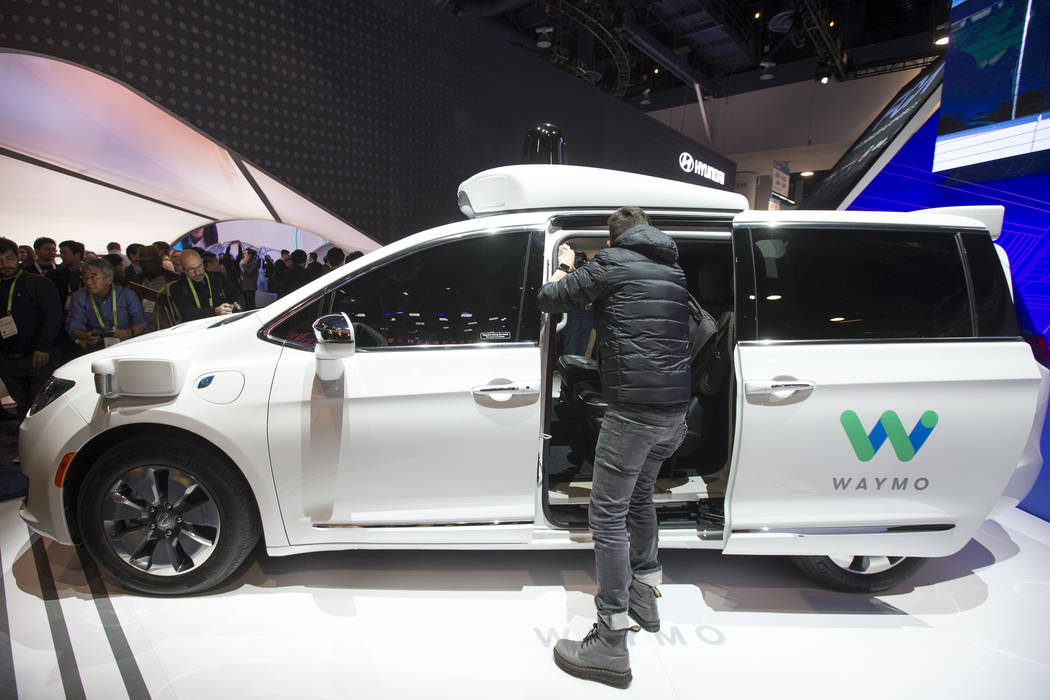 Attendees browse over a self-driving car by Waymo, Google's sister company, on display at the Fiat Chrysler Automobiles booth on day one of CES at the Las Vegas Convention Center in Las Vegas on T ...