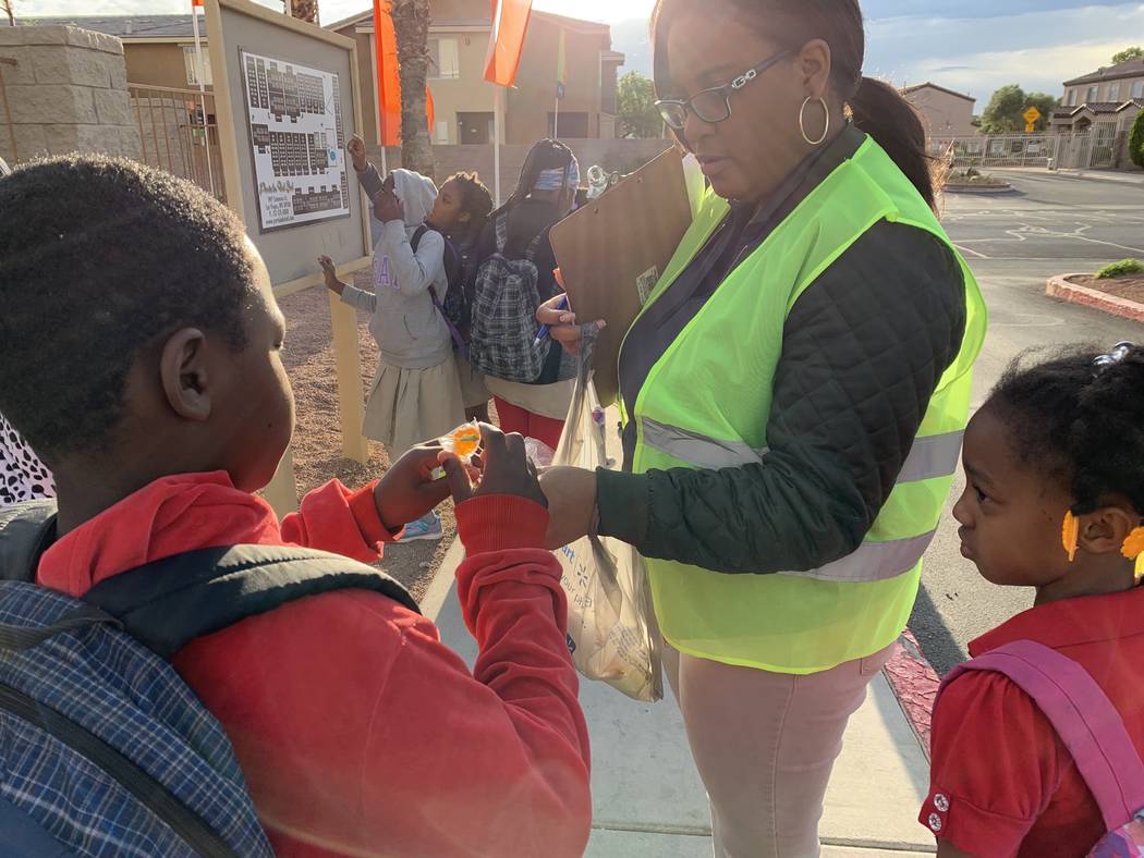 Elease Johnson hands out lollipops to students before their walk to Detwiler Elementary. (Mia ...