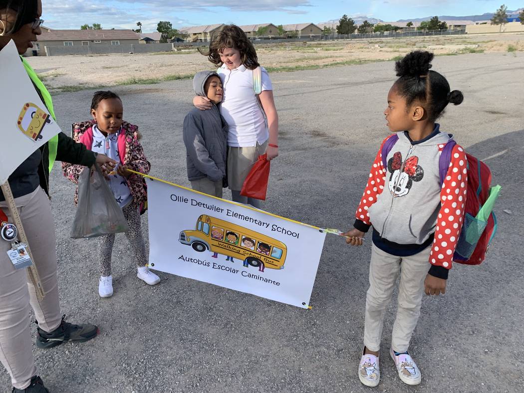 Students walking with Johnson hold signs to let bypassers know they're walking to school. (Mia ...