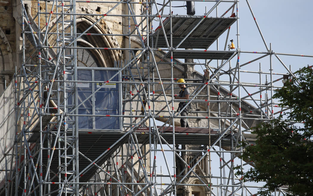 A man works on the scaffolding on the facade of the Notre Dame Cathedral in Paris, Thursday, Ap ...