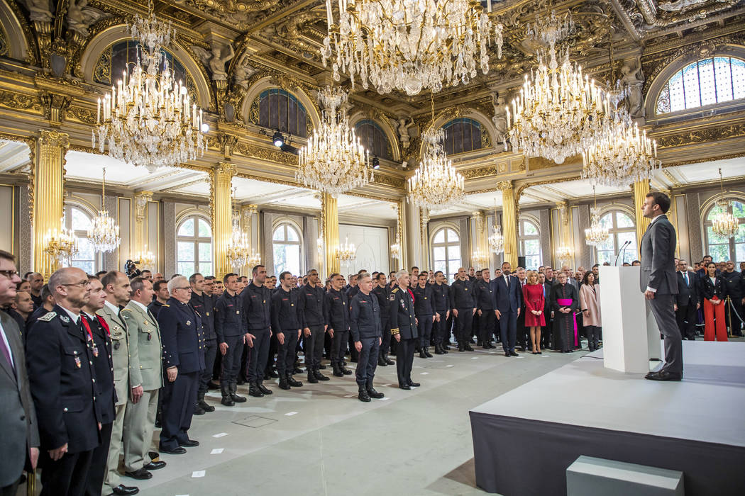 French President Emmanuel Macron stands at attention after addressing Paris Firefighters' briga ...