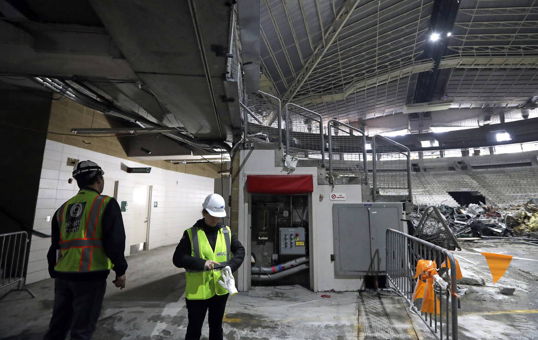 A worker glances down an existing hallway adjacent to the interior of KeyArena in the early sta ...