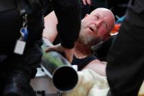 Police attempt to get the hands of a protestor out of a pipe at Oxford Circus in London, Friday ...