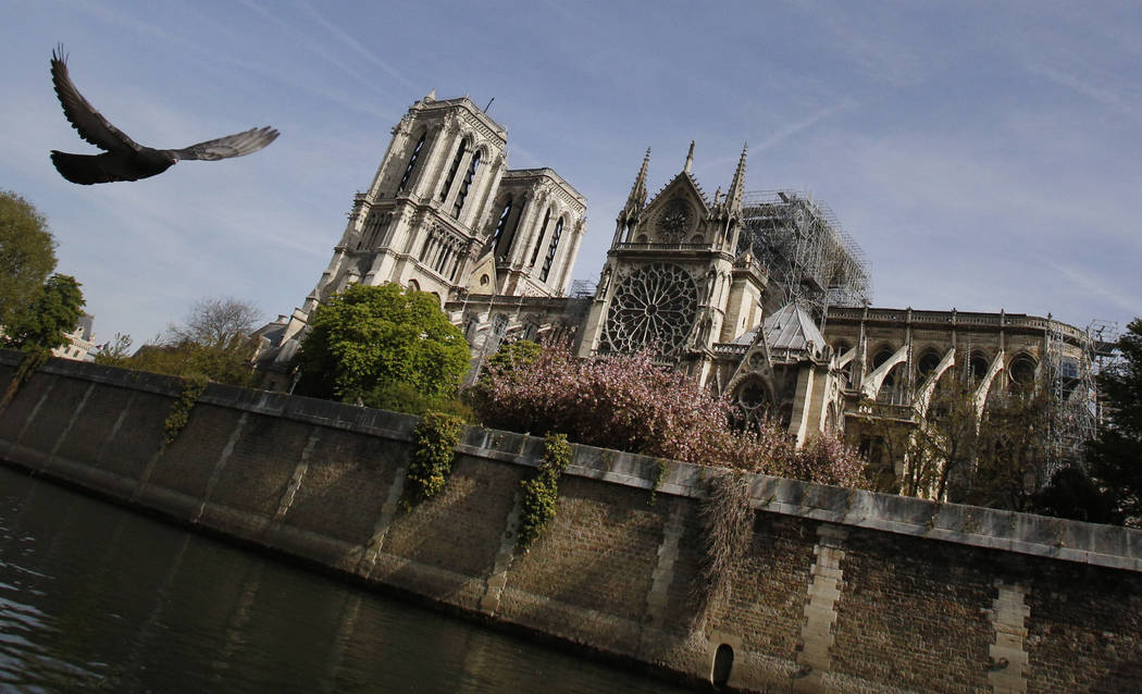 A bird flies past the Notre Dame Cathedral in Paris, Thursday, April 18, 2019. Nearly $1 billio ...