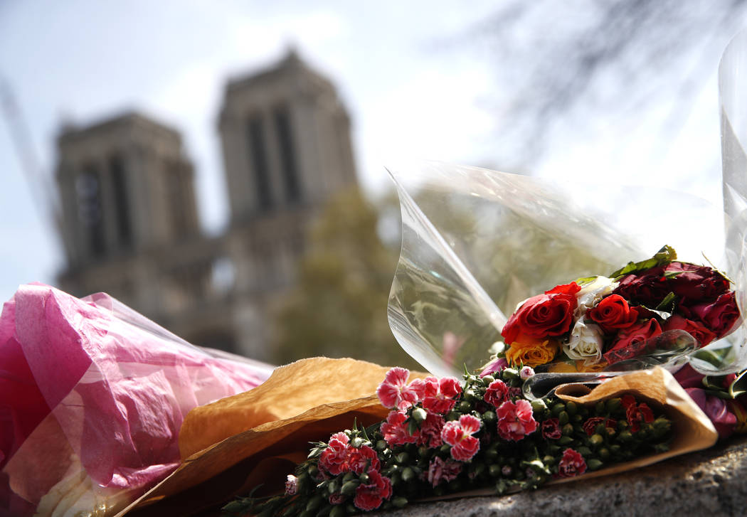 Flowers and tributes are left outside the Notre Dame Cathedral in Paris, Thursday, April 18, 20 ...