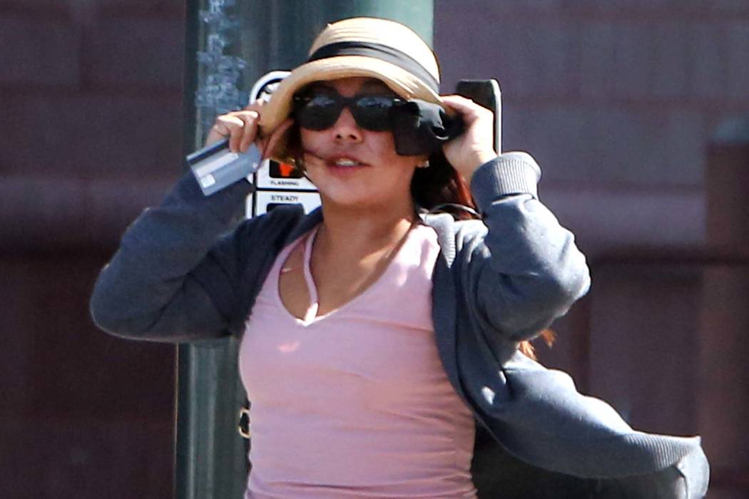 A pedestrian holds on to her hat in strong winds as she waits to cross Clark Avenue on Thursday ...