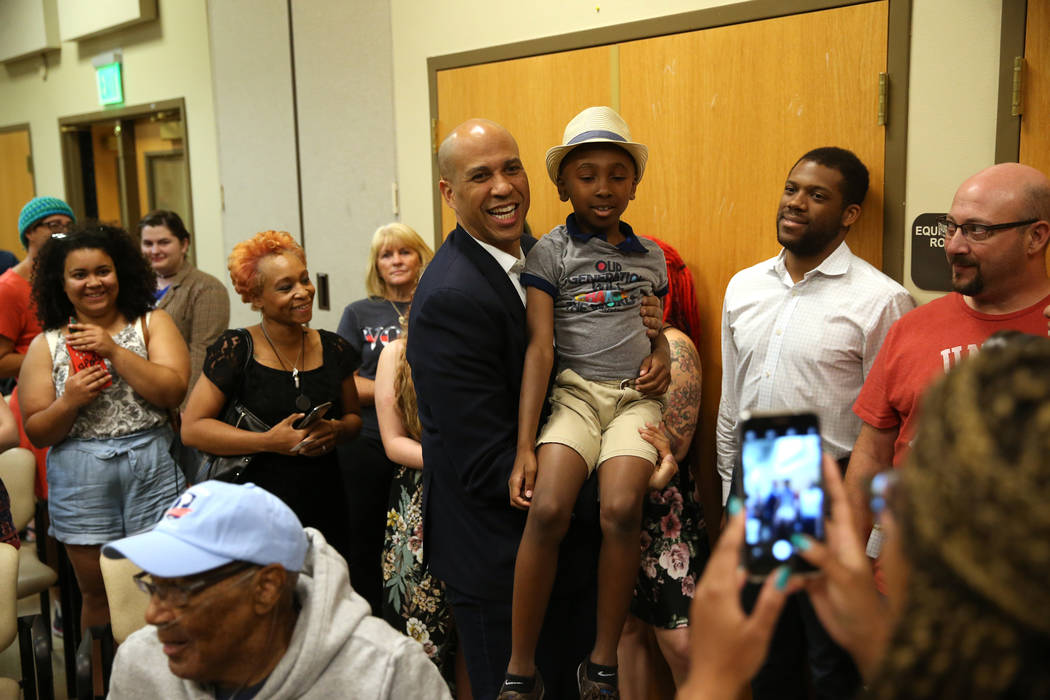 Democratic presidential candidate Sen. Cory Booker, D-N.J., center, takes a photo with Justice ...