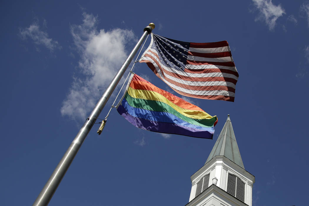 A gay pride rainbow flag flies along with the U.S. flag in front of the Asbury United Methodist ...