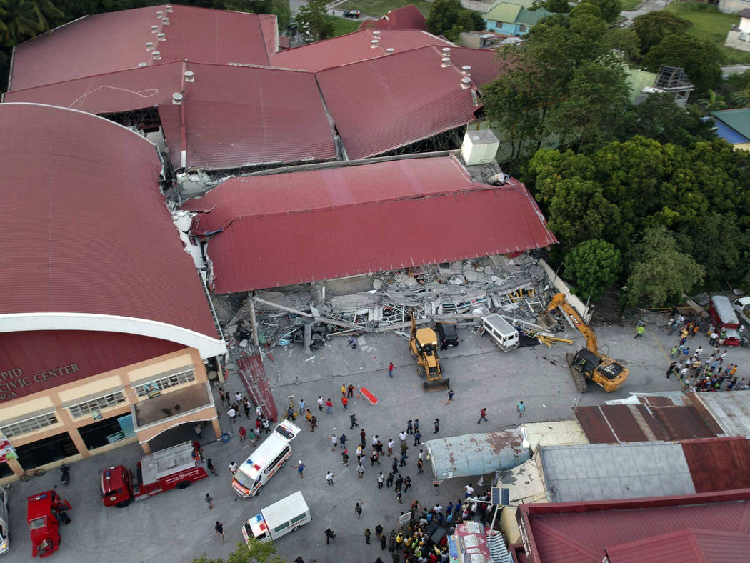 Workers use heavy equipment to clear an area as rescue efforts continue for people still trappe ...