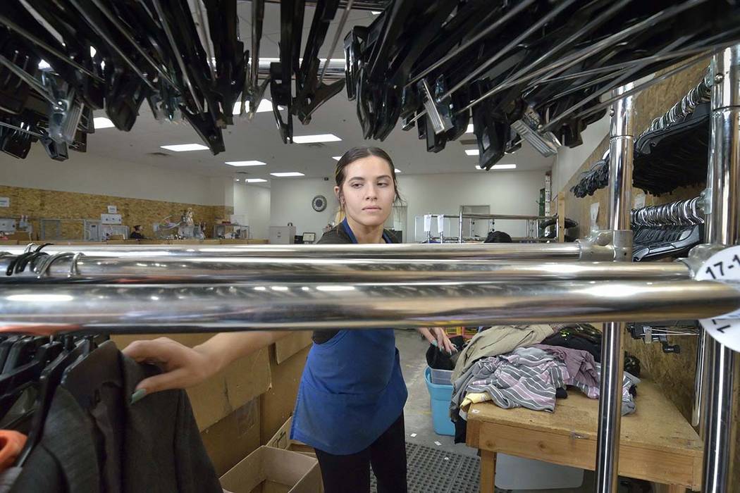 Merchandise processor Kassandra Van Duyne hangs sorted clothes in the warehouse at the Goodwill ...