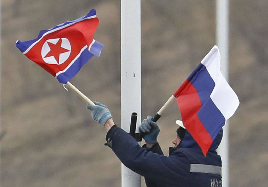 A worker adjusts the flag of Russia and North Korea along the road in Russky Island, off the so ...