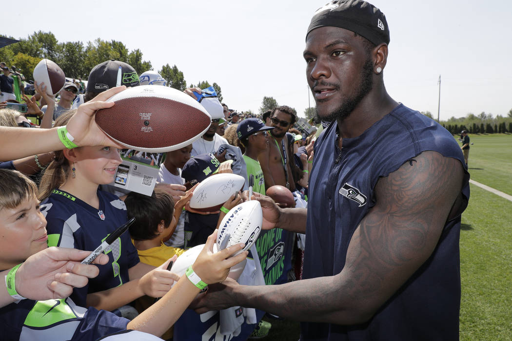 Seattle Seahawks defensive end Frank Clark signs autographs following NFL football training cam ...