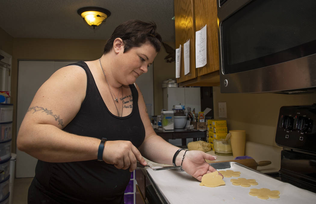 Owner of Cakes, Cookies and Creations Jessica Dejarnett places cut out sugar cookies to bake in ...