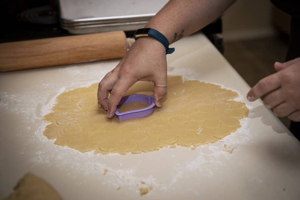 Owner of Cakes, Cookies and Creations Jessica Dejarnett cuts out shapes from cookie dough to ba ...