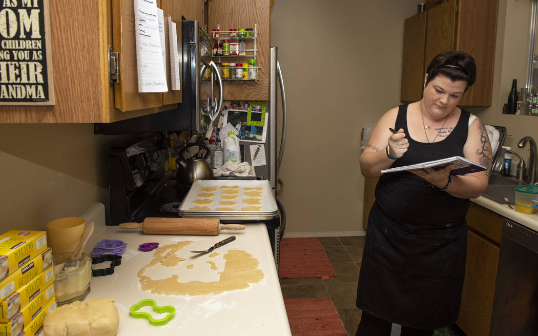 Owner of Cakes, Cookies and Creations Jessica Dejarnett writes in her planner as she bakes suga ...
