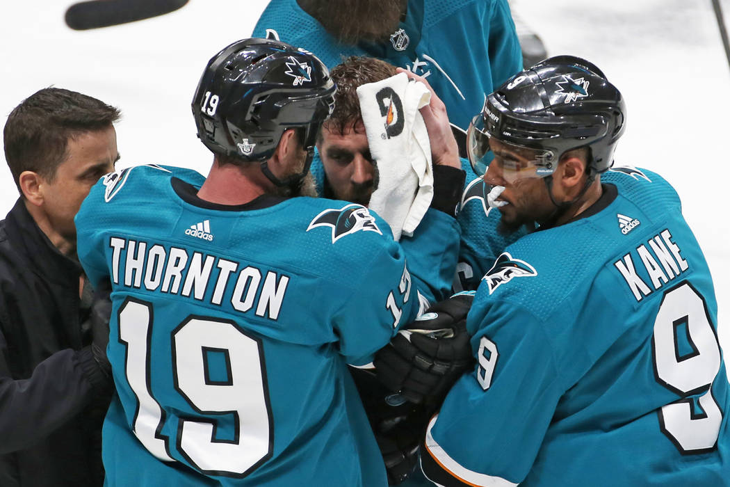 Sharks center Joe Pavelski, middle, is helped off the ice by Sharks left wing Evander Kane (9) ...