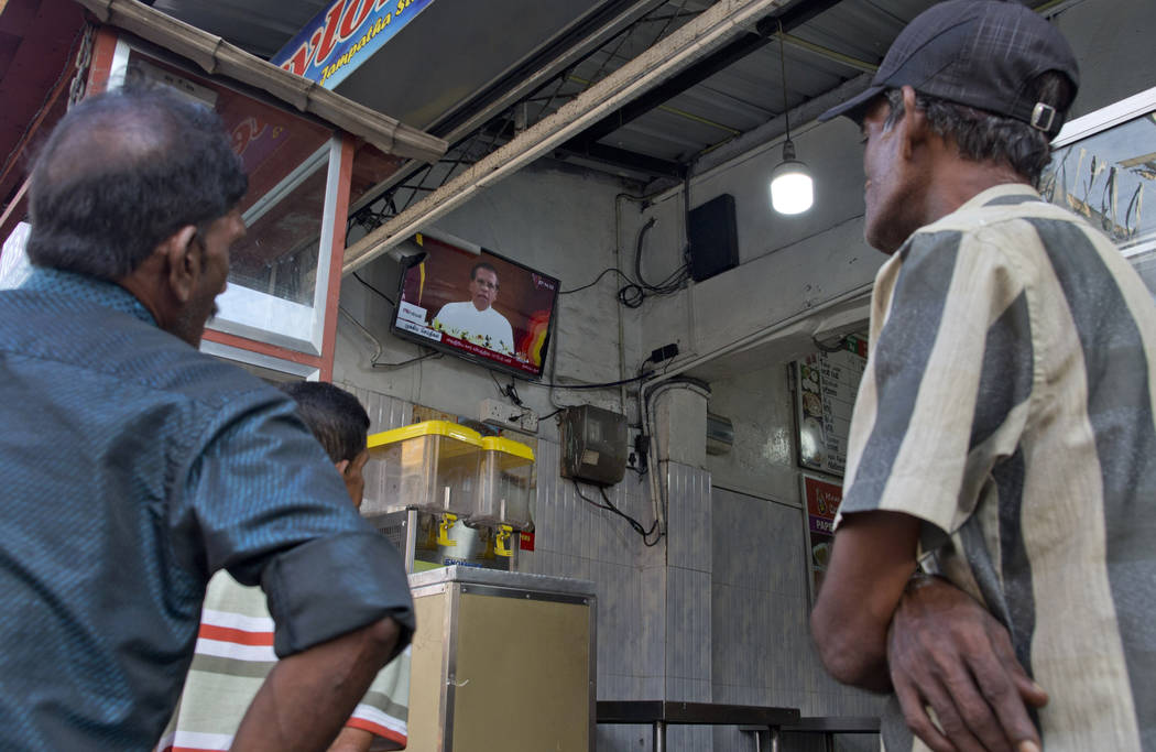 People gather around a television in a cafe showing Sri Lankan President Maithripala Sirisena's ...