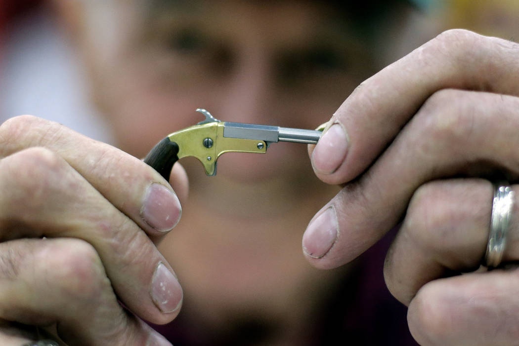 Bob McGinnis, of Cross Plains, Wis., holds a miniature gun he has made at a display of the Mini ...