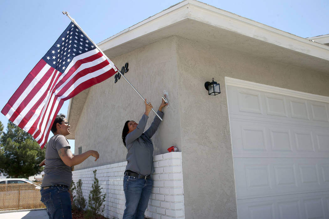 Ana Martinez, a veteran who was homeless two years ago, hangs the American flag for the first t ...