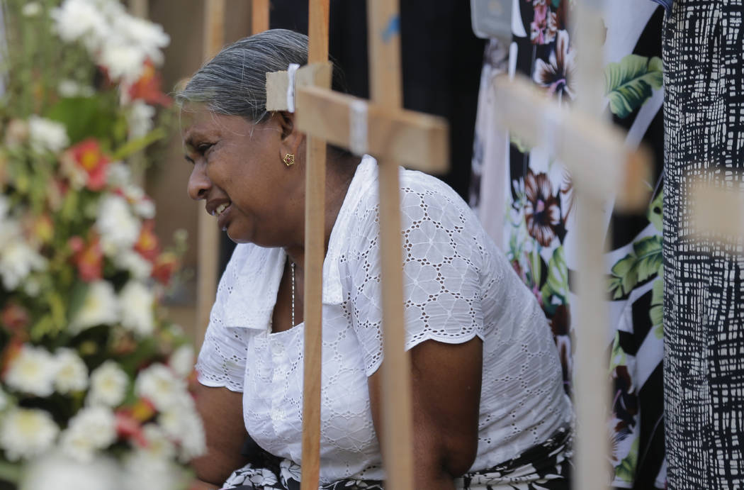 An elderly Sri Lankan woman cries sitting next to the grave of her family member who died in Ea ...