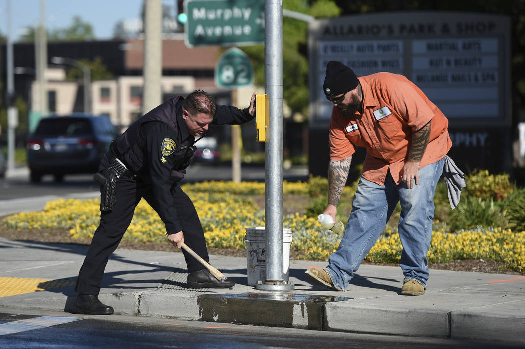 Police and road crews work to clean up the scene after a car crash at the intersection of El Ca ...