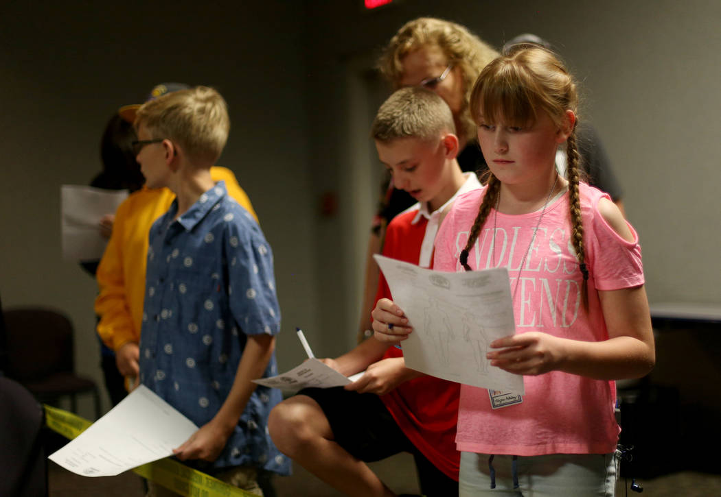 Alyssa Holliday, 11, examines a fake crime scene next to her twin Alex Holliday, 11, at the cor ...