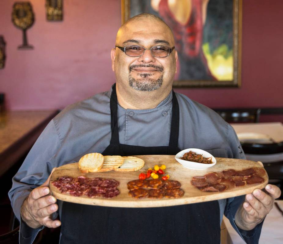 Executive chef Ariel Zuniga holds salchichon, acorn fed iberico salami, chorizo iberico, dry ib ...