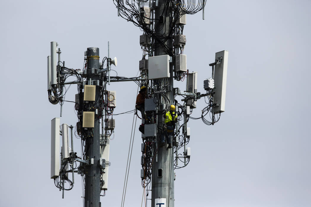 Workers install equipment April 17, 2019, on a communications tower in Philadelphia. On Friday, ...