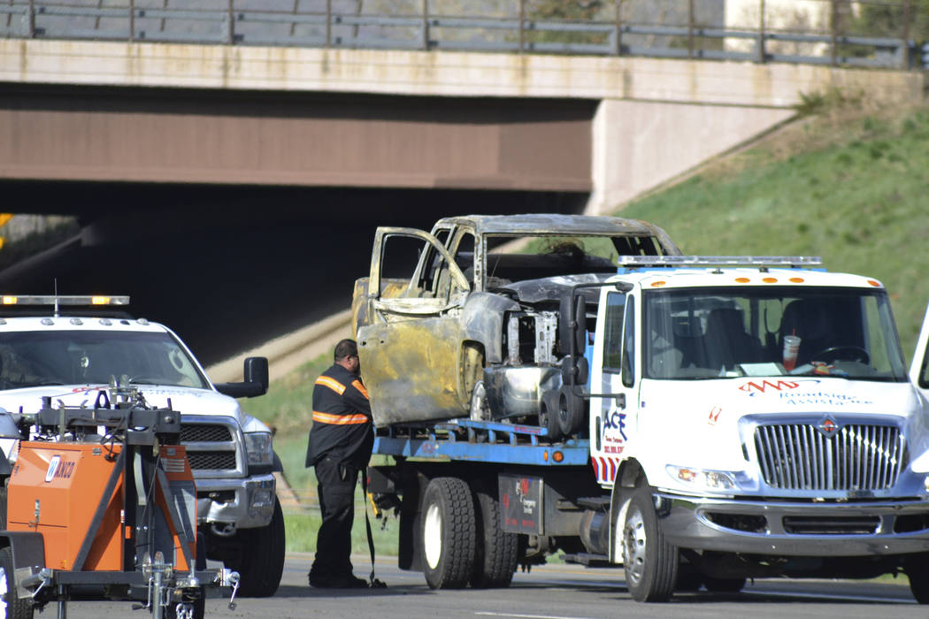 A tow truck driver removes a burned out car at the scene of a fiery crash on I-70 near Colorado ...