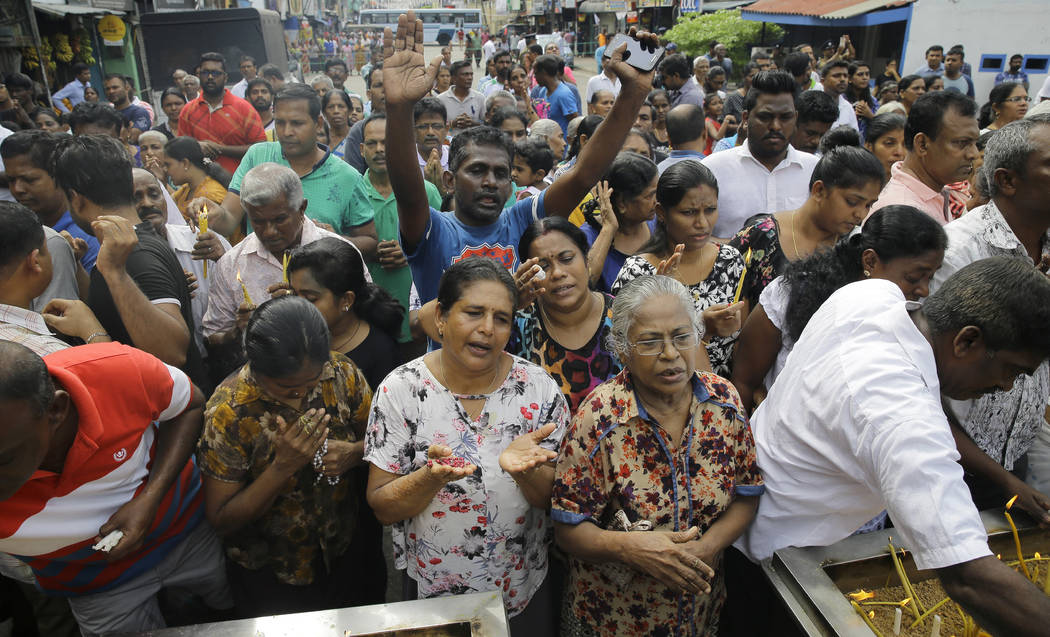 Sri Lankan Catholics pray standing on a road during a brief holly mass held outside the explode ...