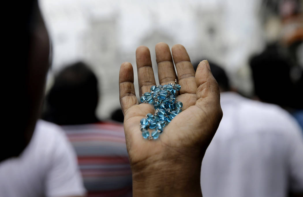 A Sri Lankan Catholic holds her rosary as she prays on a road during a brief holly mass held ou ...