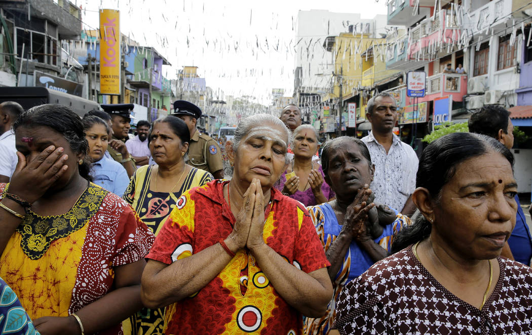 Sri Lankan Catholics pray standing on a road during a brief holly mass held outside the explode ...