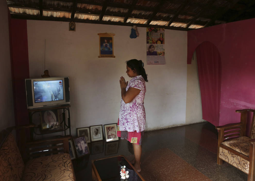 A Sri Lankan Christian catholic woman prays inside her home watching live transmission of Sri L ...