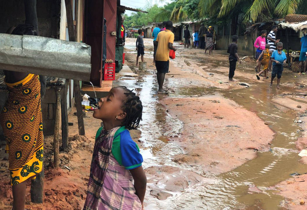 A child drinks water from a gutter during floods due to heavy rains in Pemba, Mozambique, Sunda ...