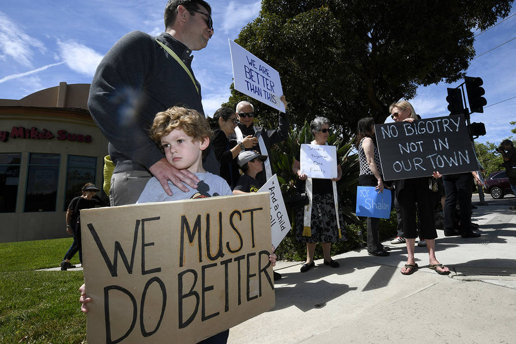 Kyle Fox, 4, and his father Brady Fox hold a sign at a vigil held to support the victims of Cha ...