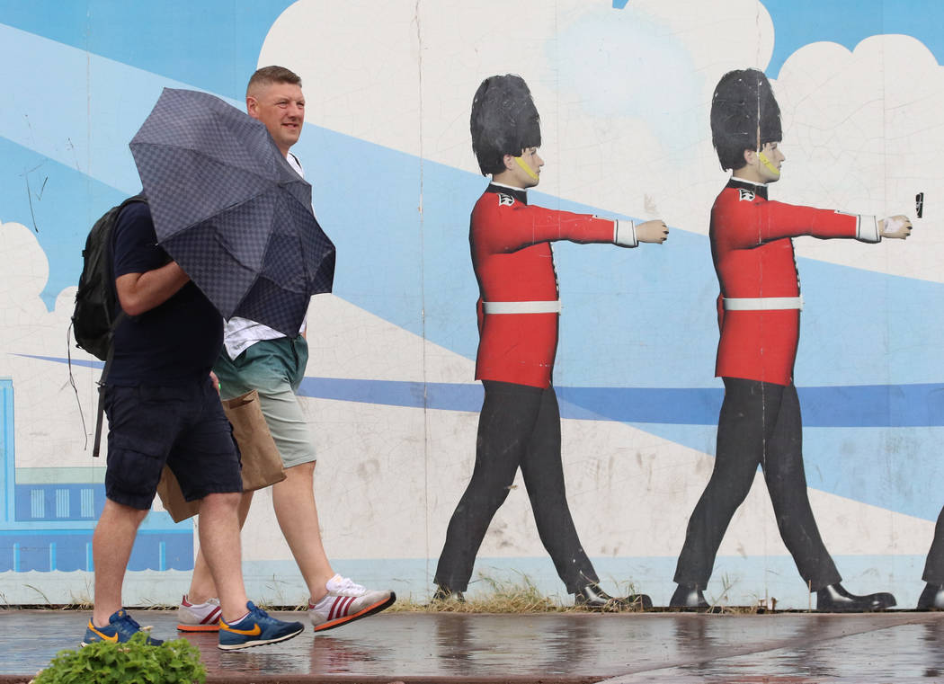 A pedestrian holds an umbrella to protect himself from heavy winds and rain as he walks along L ...