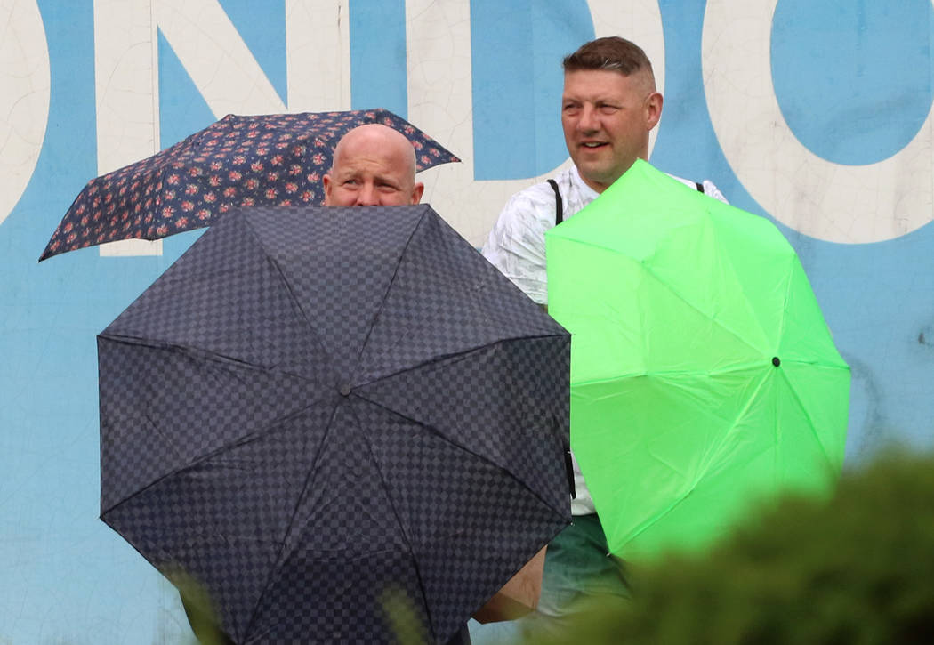 Pedestrians hold umbrellas to protect themselves from heavy winds and rain as they walk along L ...