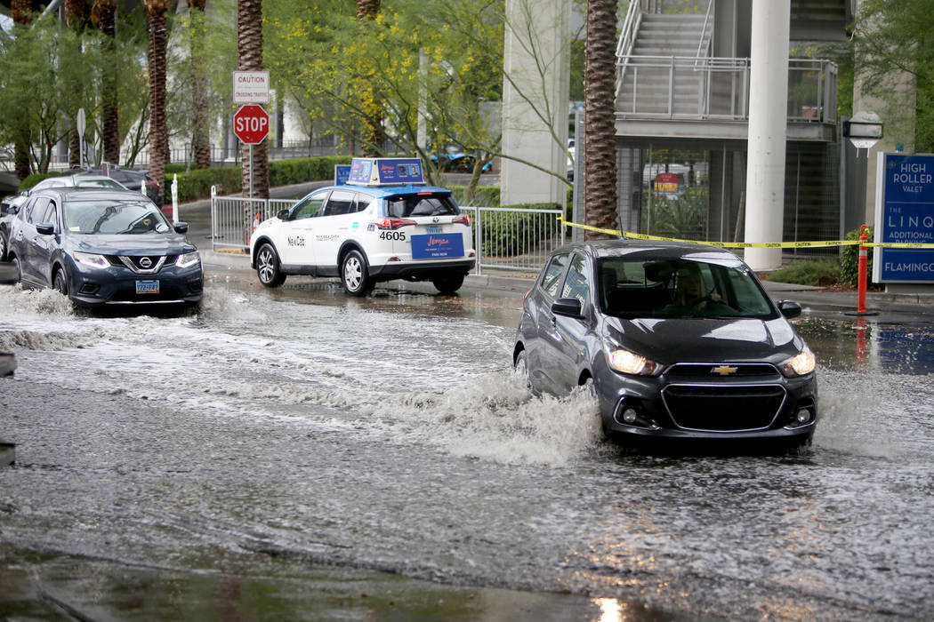 Cars drive through the flooding at The Linq Hotel and casino parking garage in Las Vegas, Monda ...