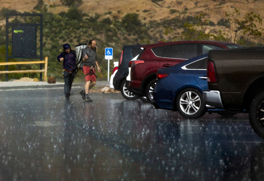 Hikers run for their vehicle as a fast-moving storm makes its way through the Red Rock Canyon N ...