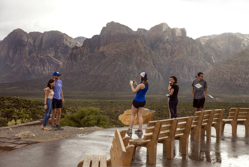 Visitors brave the rain for some photos as a fast-moving storm makes its way through the Red Ro ...