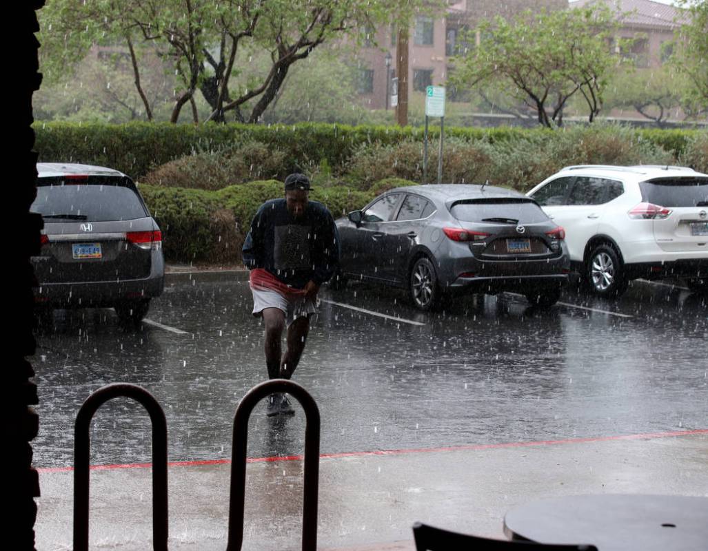 Khirie Williams of Las Vegas runs through a downpour at Summerlin Center Pointe Plaza in Las Ve ...