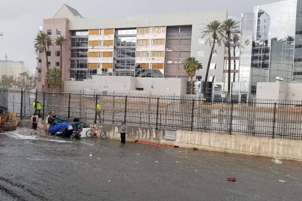 People try to get out of the rain in a wash near the Hard Rock Hotel in Las Vegas, Monday, Apri ...