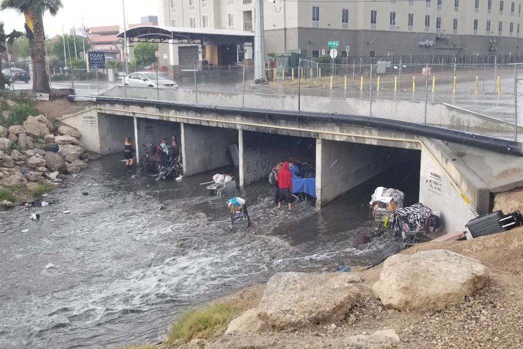 People try to get out of the rain in a wash near Flamingo Road and Palos Verdes Street in Las V ...