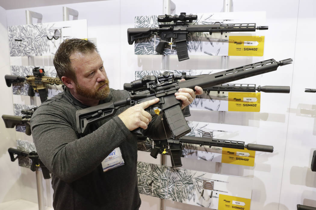 Bryan Oberc, Munster, Ind., tries out an AR-15 from Sig Sauer in the exhibition hall at the Nat ...