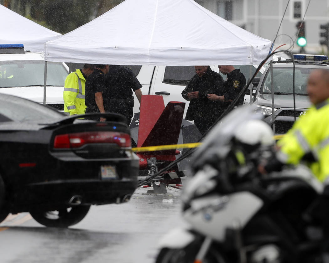 Investigators stand around the wreckage of a helicopter, Monday, April 29, 2019, in Kailua, Haw ...