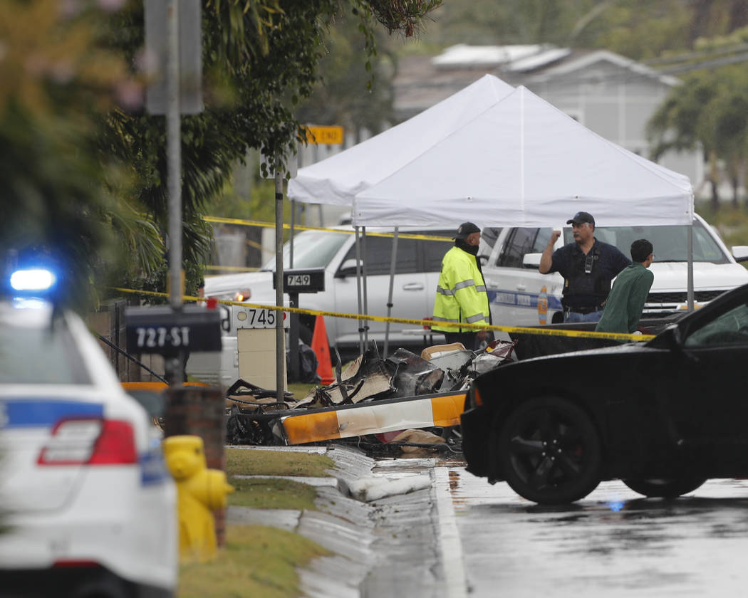 Investigators stand around the wreckage of a helicopter, Monday, April 29, 2019, in Kailua, Haw ...