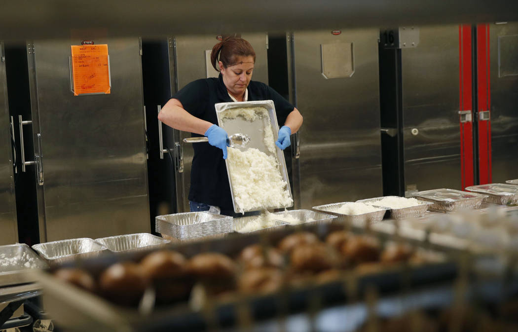 In this March 25, 2019, photo, Lisa Garcia packs up uneaten food from the convention area at th ...