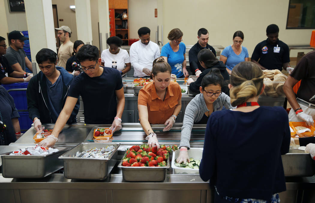 In this March 26, 2019, photo, volunteers put together food trays at Three Square, a food bank ...