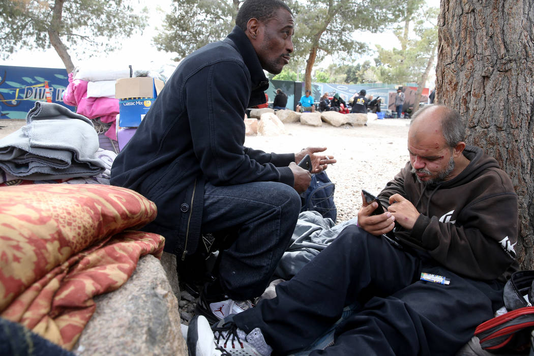 Hachet, right, works on a phone belonging to Michael Fletcher at the City of Las Vegas Courtyar ...