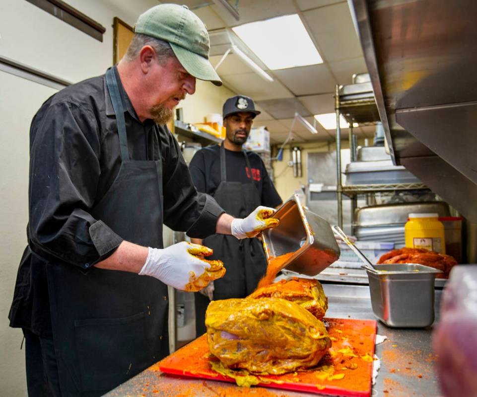 New employee Ron Cochran receives some meat rub training from kitchen prep/smoker Anthony McMah ...